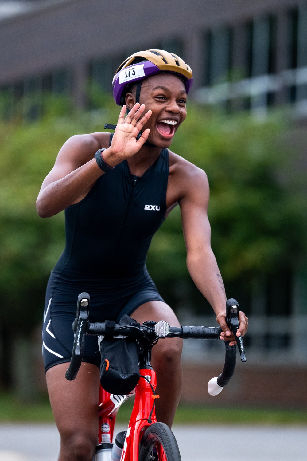 A cyclist waving mid-race